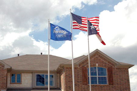 Custom Meritage Homes flag flying with the U.S. flag and Texas state flag in front of a model home