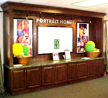 A custom cabinet in a Portrait Homes sales office displaying the company logo and photography