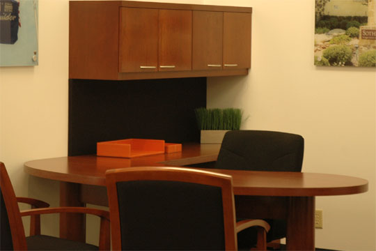 A typical Novikoff Furniture Metaplan desk in a dark wood color with two guest chairs an one executive chair