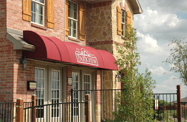 A red awning with a curved front mounted on a model home